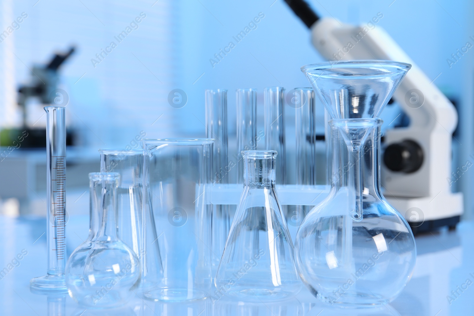 Photo of Laboratory analysis. Different glassware and microscope on white table indoors