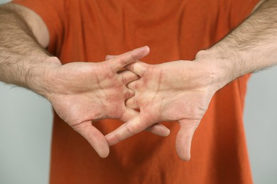 Photo of Man cracking his knuckles on light grey background, closeup. Bad habit