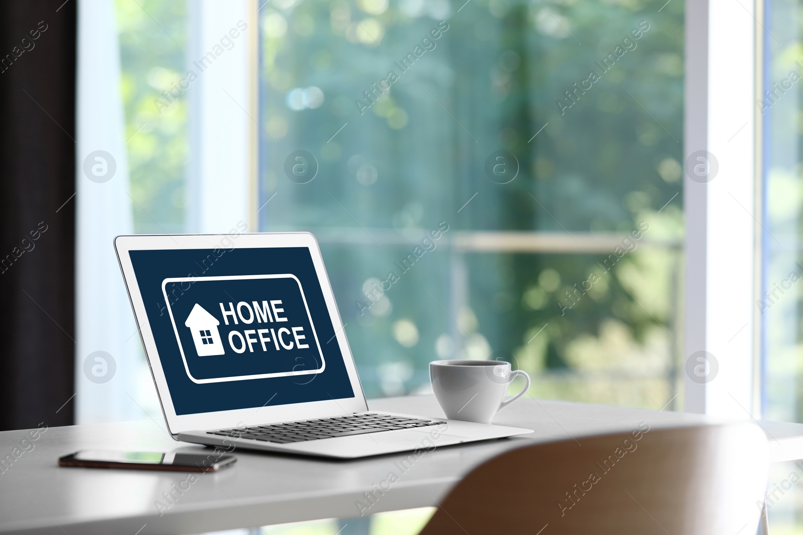 Image of Modern laptop with text HOME OFFICE on white table indoors