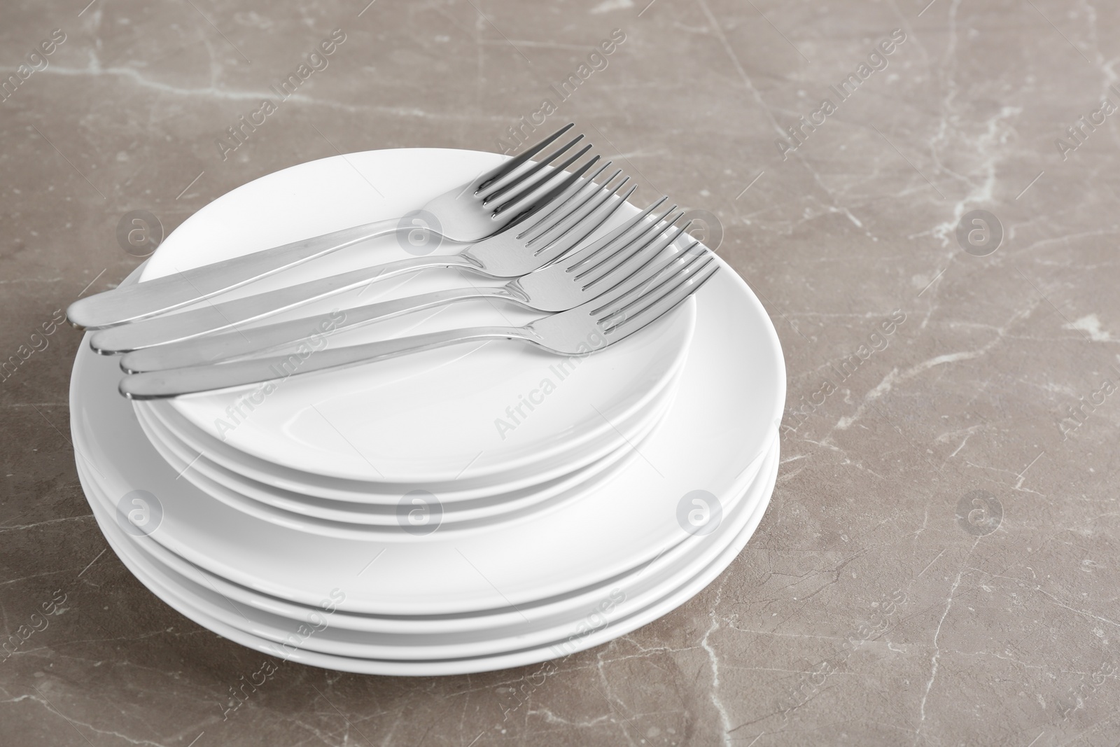 Photo of Stack of ceramic dishware with cutlery on grey background