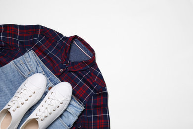 Stylish shirt, jeans and sneakers on white background, flat lay. Space for text