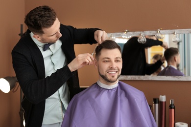 Photo of Professional hairdresser working with client in beauty salon