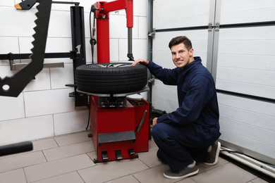 Man working with tire fitting machine at car service