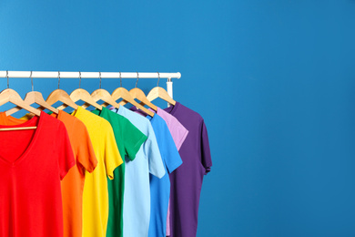 Photo of Bright clothes on blue background, space for text. Rainbow colors