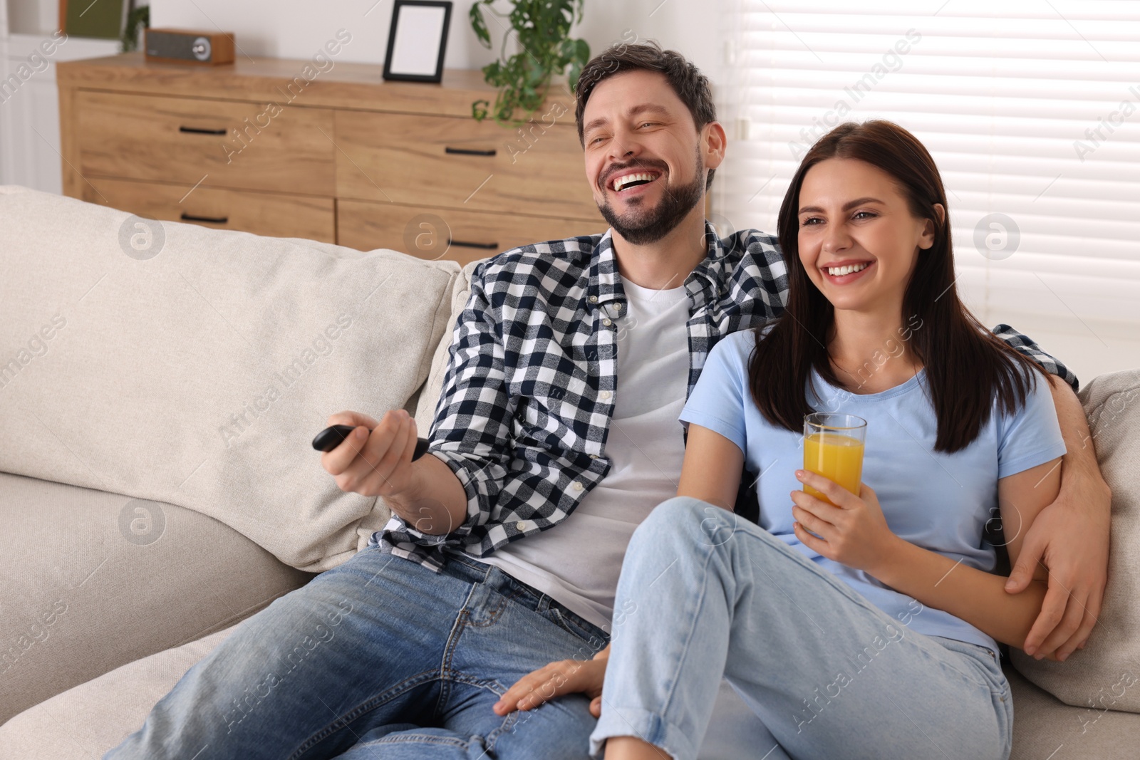 Photo of Couple watching comedy via TV and laughing at home