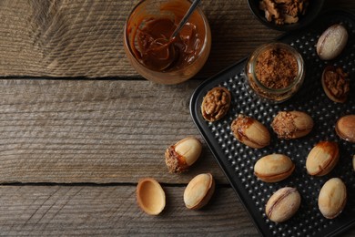 Freshly baked homemade walnut shaped cookies, boiled condensed milk and nuts on wooden table, flat lay. Space for text