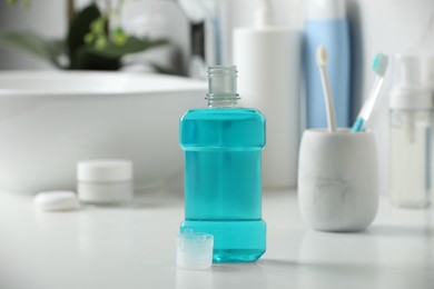 Photo of Bottle of mouthwash on white countertop in bathroom