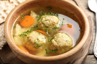 Photo of Bowl of Jewish matzoh balls soup on wooden table, closeup