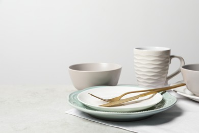Photo of Beautiful ceramic dishware, cup and cutlery on light grey table, space for text