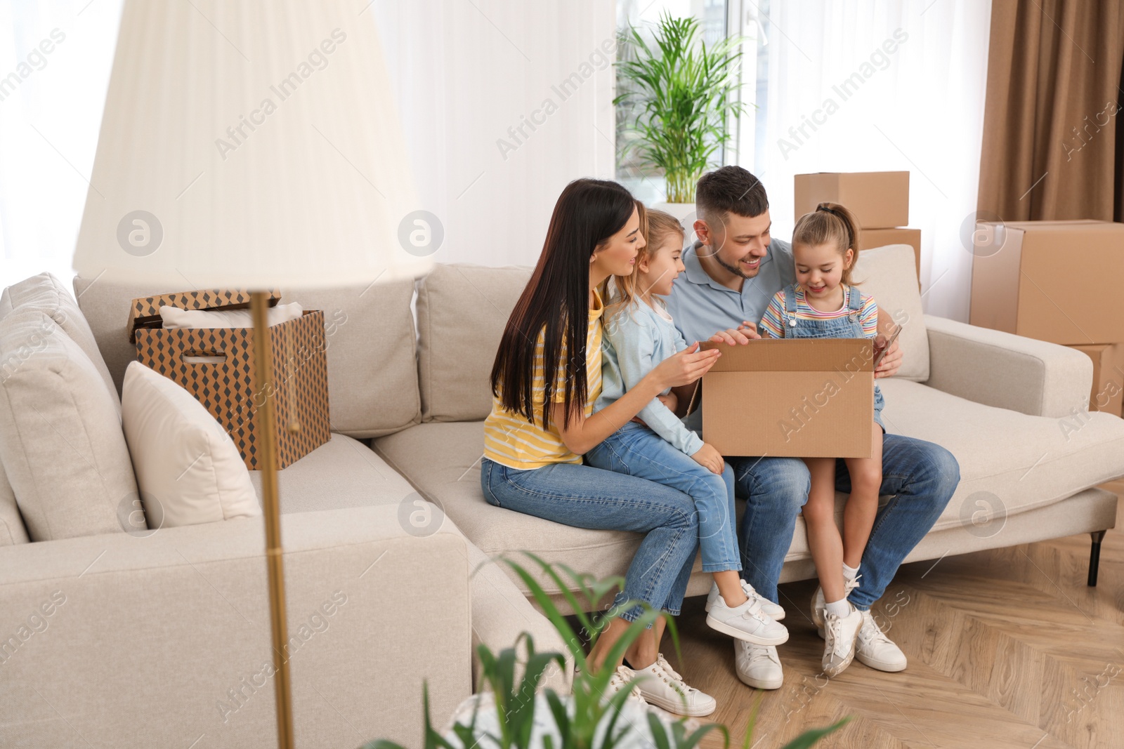 Photo of Happy family unpacking moving box at their new house