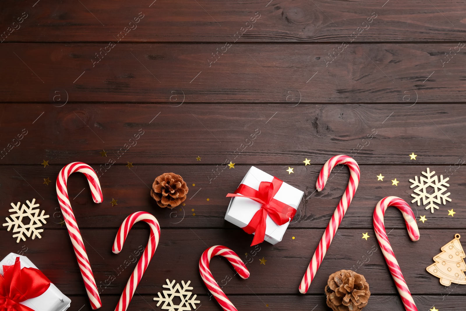 Photo of Flat lay composition with candy canes and Christmas decor on wooden table. Space for text