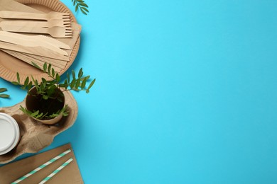 Flat lay of paper and wooden tableware with green twigs on turquoise background, space for text. Eco friendly lifestyle