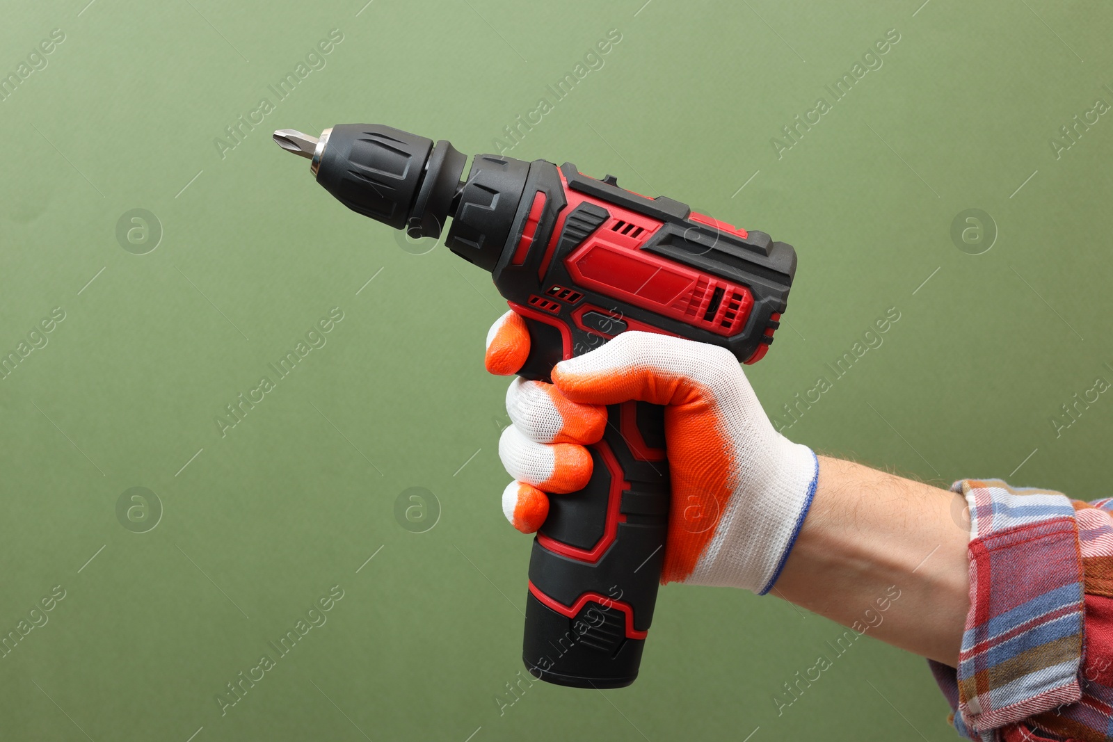 Photo of Handyman holding electric screwdriver on pale green background, closeup