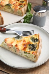 Photo of Piece of delicious homemade salmon quiche with broccoli and fork on plate
