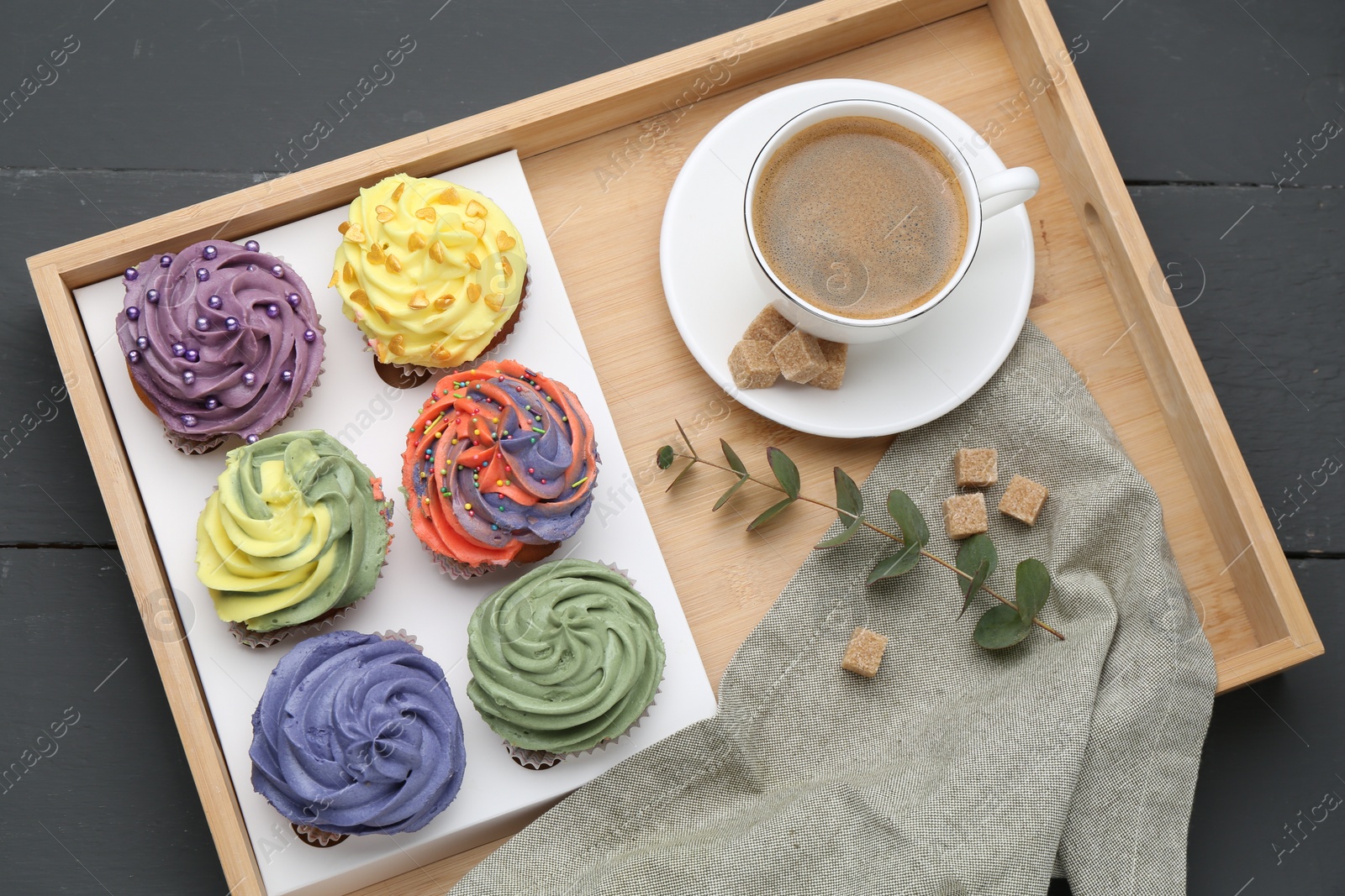 Photo of Different colorful cupcakes and coffee on grey table, top view