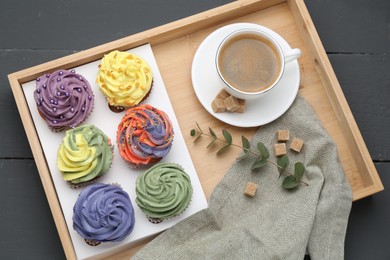 Different colorful cupcakes and coffee on grey table, top view