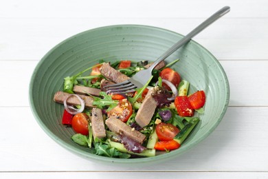 Delicious salad with beef tongue, vegetables and fork on white wooden table