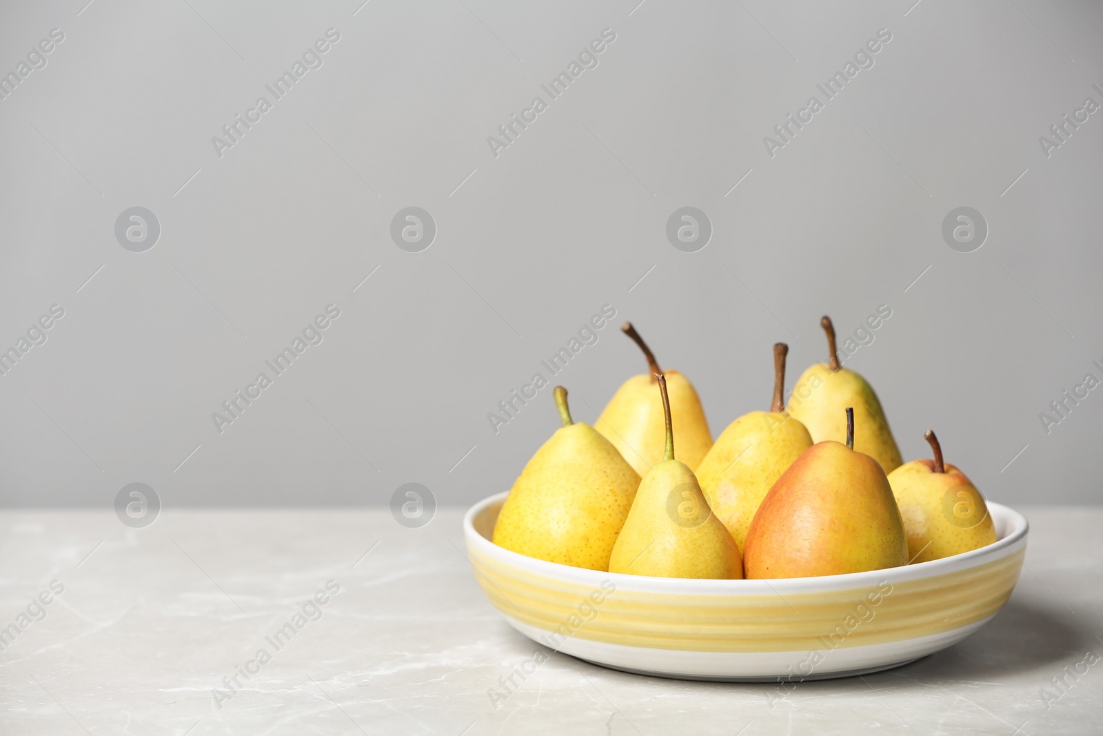 Photo of Plate with pears on table against grey background. Space for text