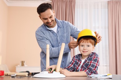 Father putting hard hat on his son at home. Repair work