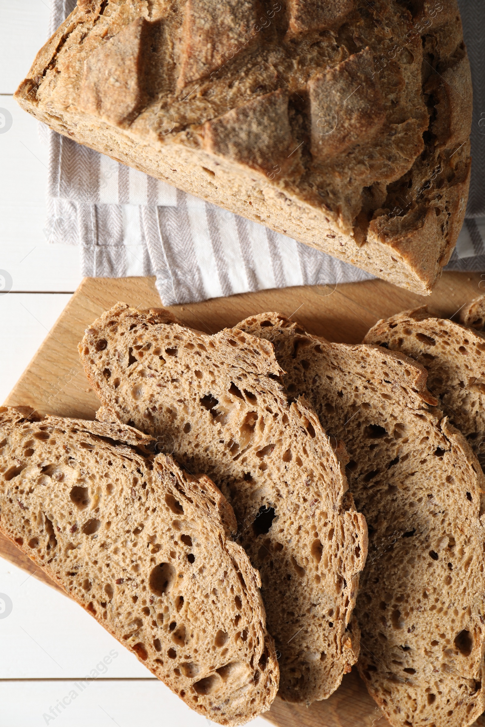 Photo of Freshly baked cut sourdough bread on white wooden table, top view