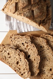 Photo of Freshly baked cut sourdough bread on white wooden table, top view