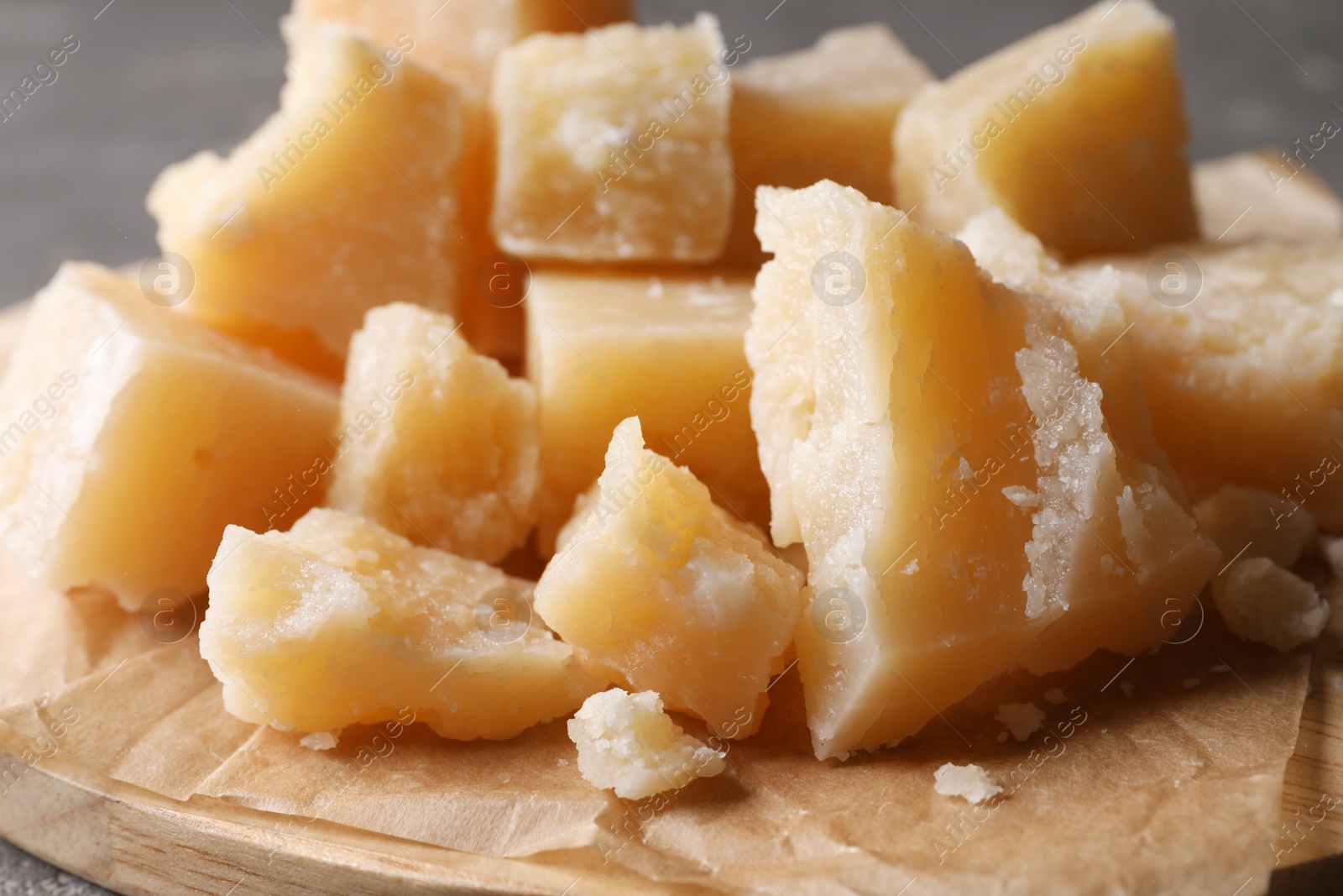 Photo of Pieces of delicious parmesan cheese on wooden board, closeup