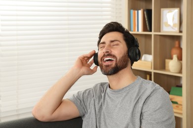 Photo of Happy man listening music with headphones indoors