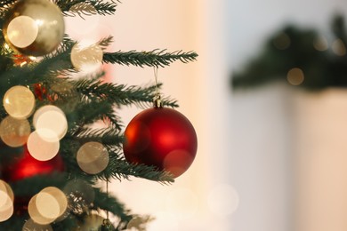 Photo of Christmas tree decorated with festive balls on light background, closeup. Space for text