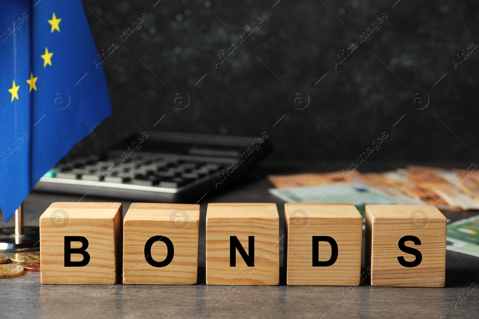 Photo of European Union flag, banknotes and word Bonds made of wooden cubes on grey table