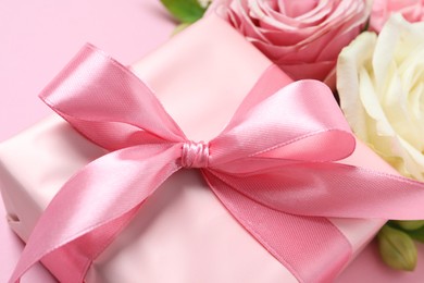 Photo of Gift box and beautiful flowers on pink background, closeup