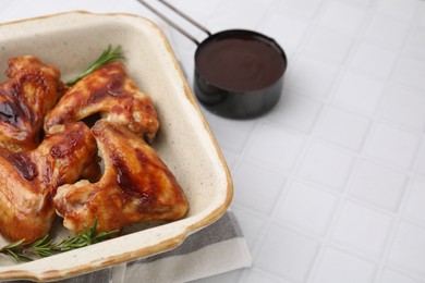 Photo of Fresh marinade, chicken wings and rosemary on white tiled table, closeup. Space for text