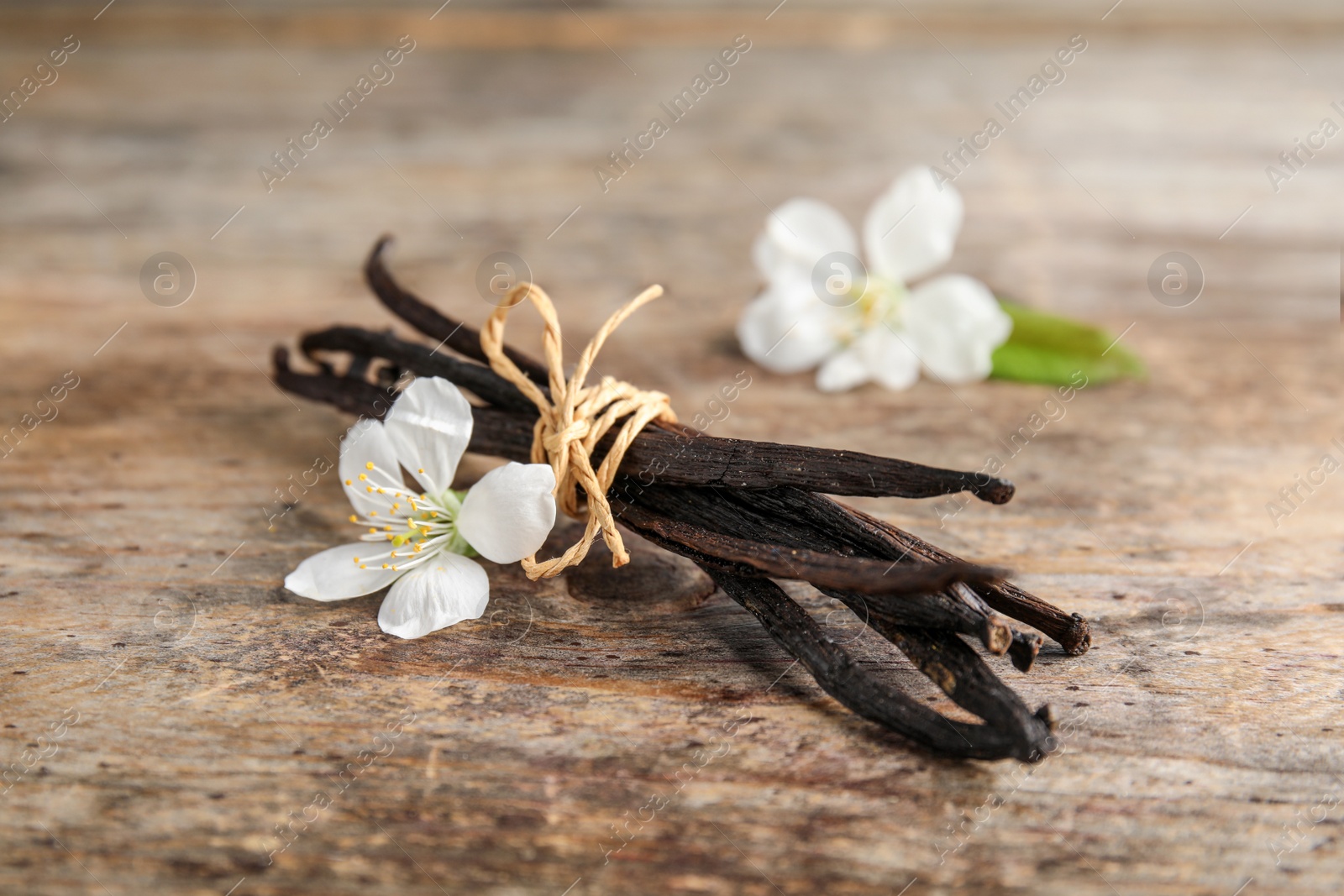 Photo of Aromatic vanilla sticks and flowers on wooden background