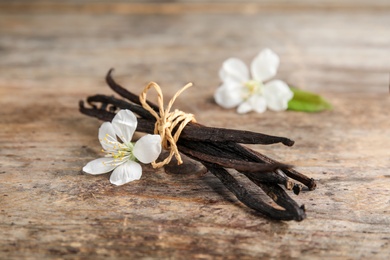 Photo of Aromatic vanilla sticks and flowers on wooden background