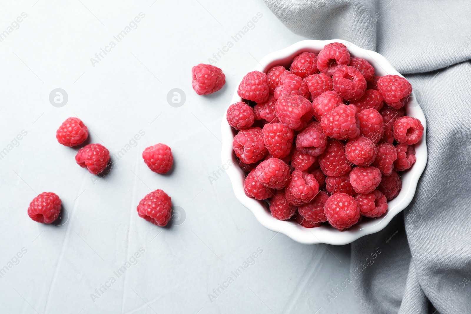 Photo of Bowl with ripe aromatic raspberries on table, top view