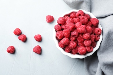 Photo of Bowl with ripe aromatic raspberries on table, top view