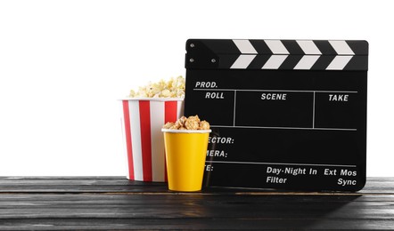 Photo of Movie clapper and buckets of tasty popcorn on wooden table against white background, space for text