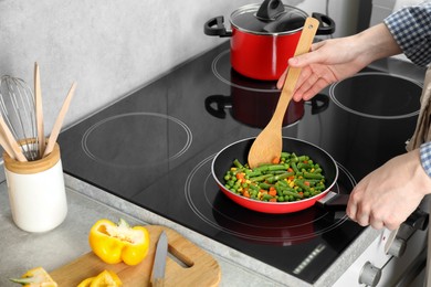 Photo of Woman cooking tasty vegetable mix in frying pan at home, closeup