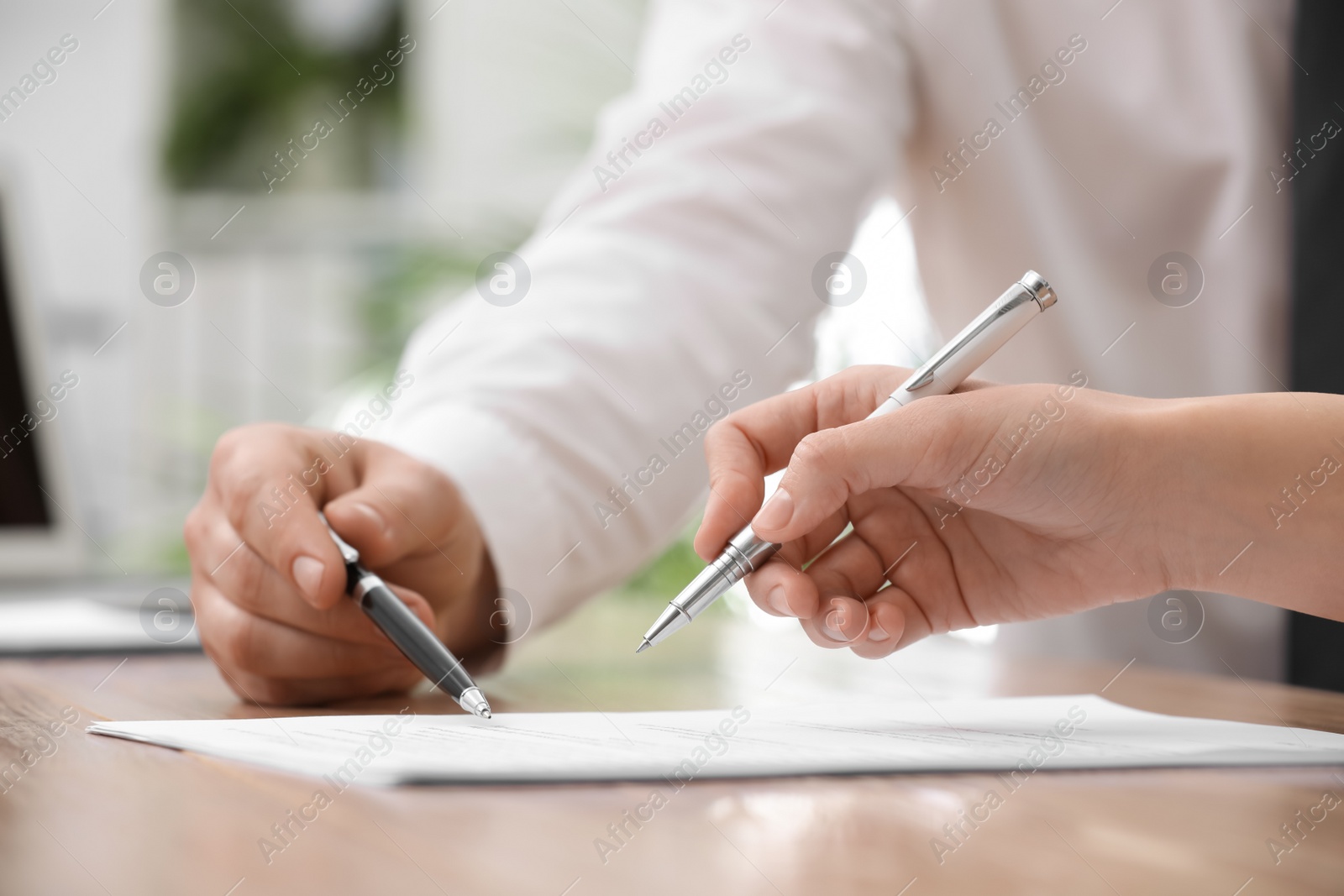 Photo of Businesspeople signing contract at table in office, closeup