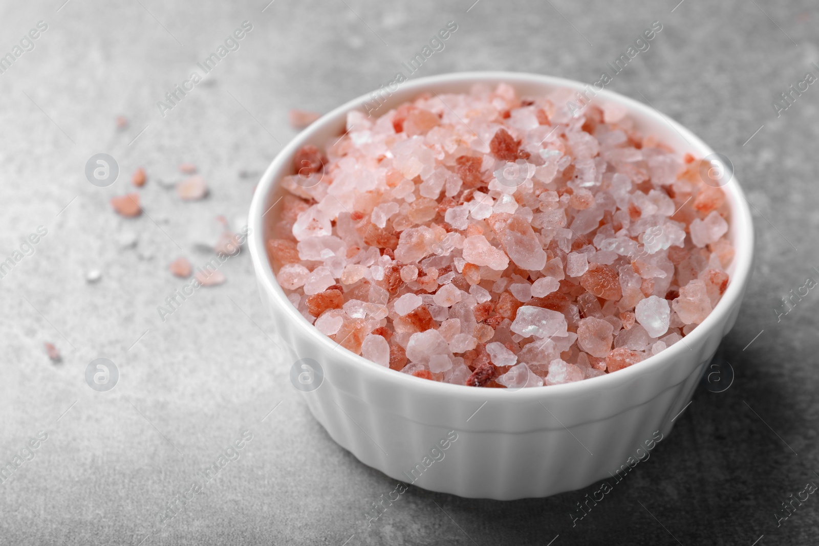 Photo of Pink Himalayan salt in bowl on grey table