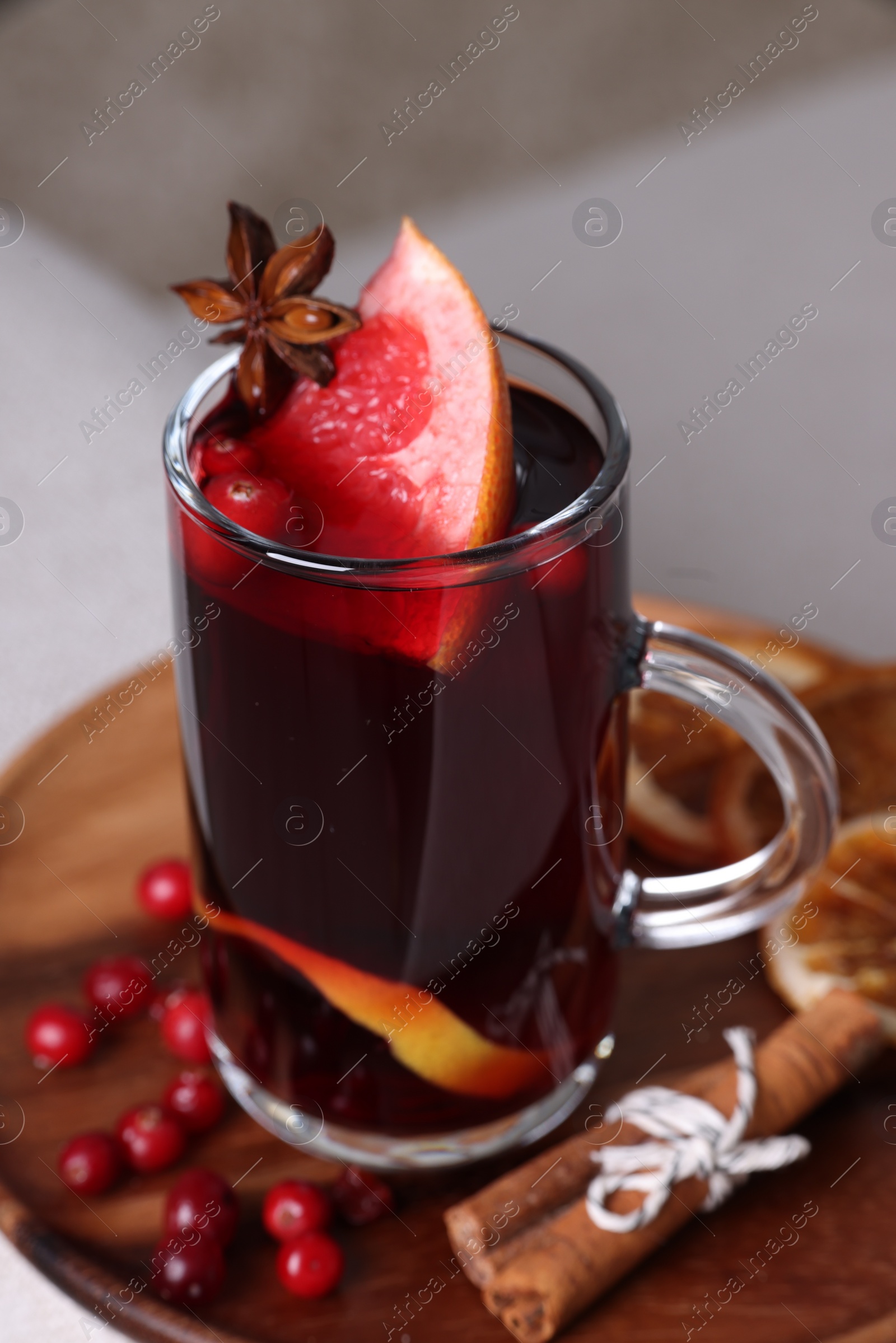 Photo of Aromatic mulled wine in cup and ingredients on sofa armrest