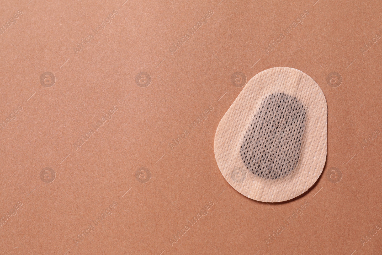 Photo of Contraceptive patch on light brown background, top view. Space for text