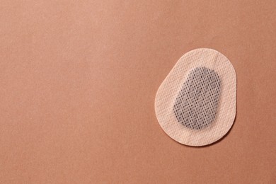 Photo of Contraceptive patch on light brown background, top view. Space for text