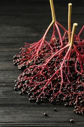 Photo of Bunches of ripe elderberries on black wooden table