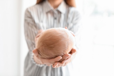 Photo of Young mother holding her newborn baby on light background