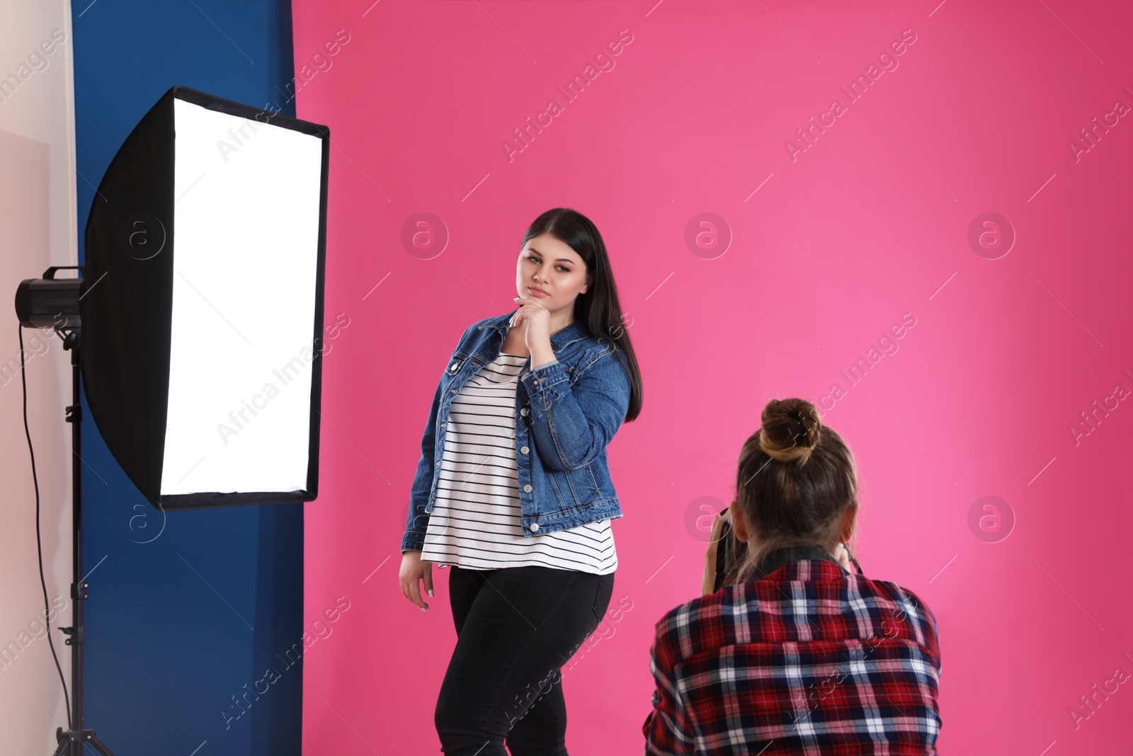 Photo of Photographer taking picture of overweight woman in studio. Plus size model
