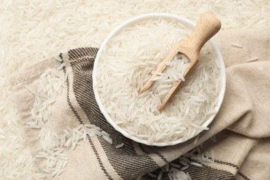 Raw basmati rice, bowl, scoop and cloth, top view