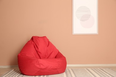 Photo of Red bean bag chair on floor near beige wall indoors