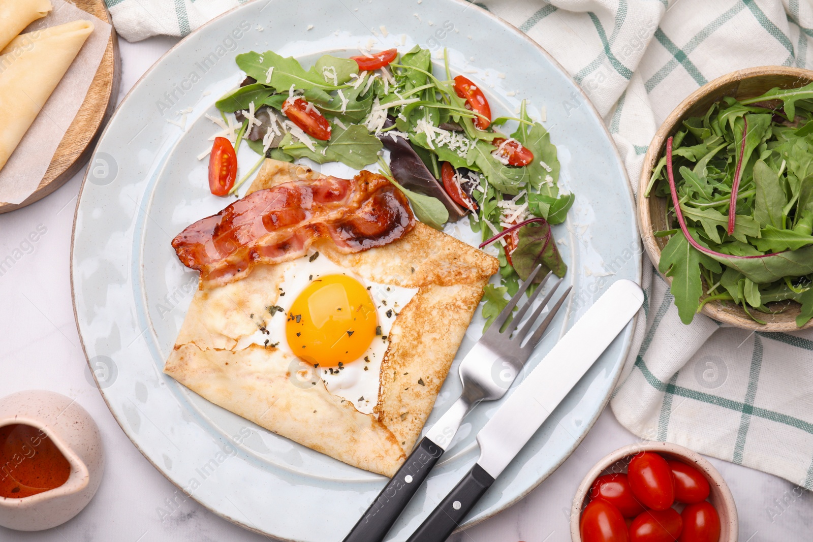 Photo of Delicious crepe with egg served on white marble table, flat lay. Breton galette