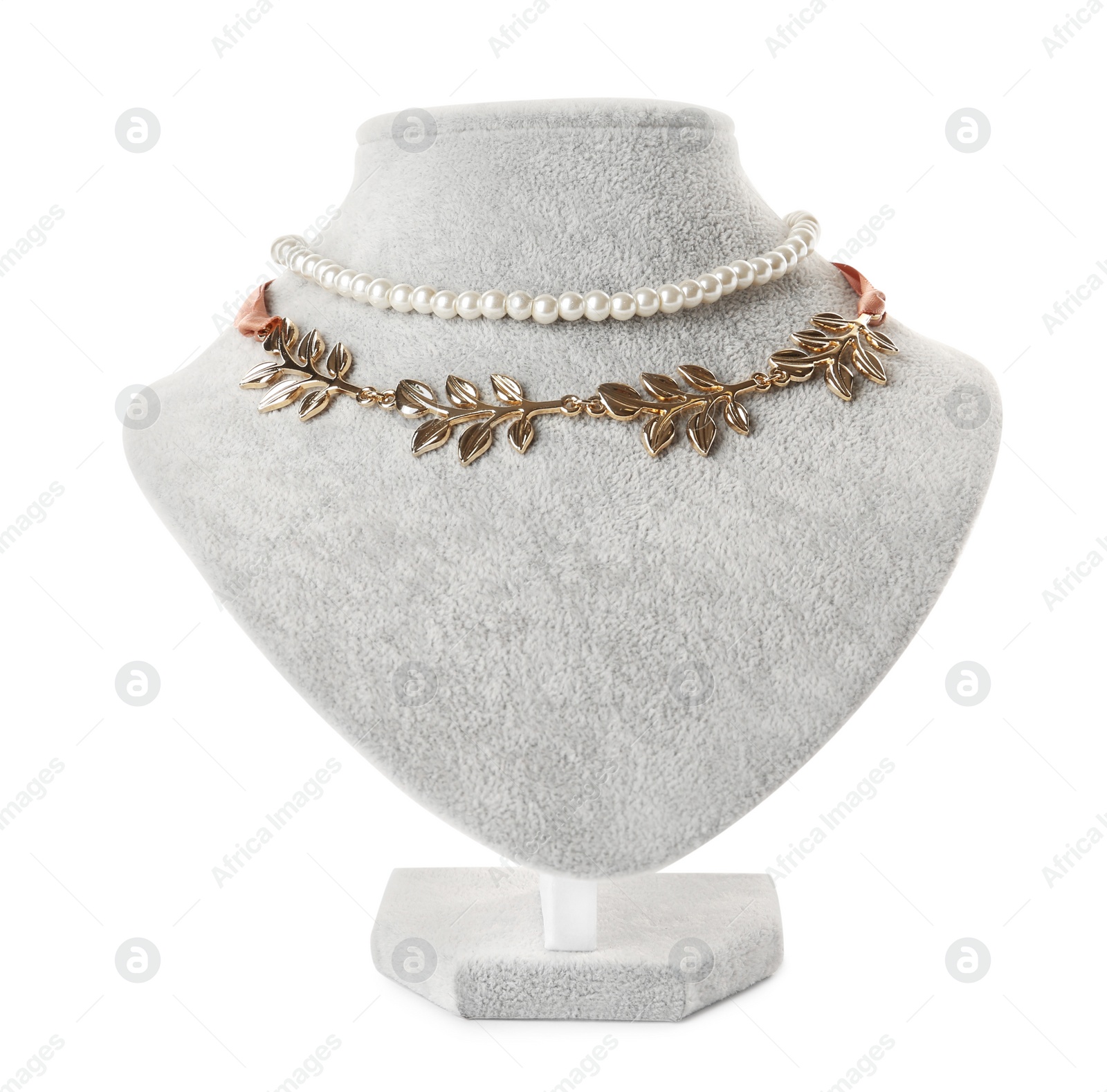 Photo of Stylish golden and pearl necklaces on jewelry bust against white background