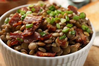 Photo of Delicious lentils with bacon and green onion in bowl, closeup